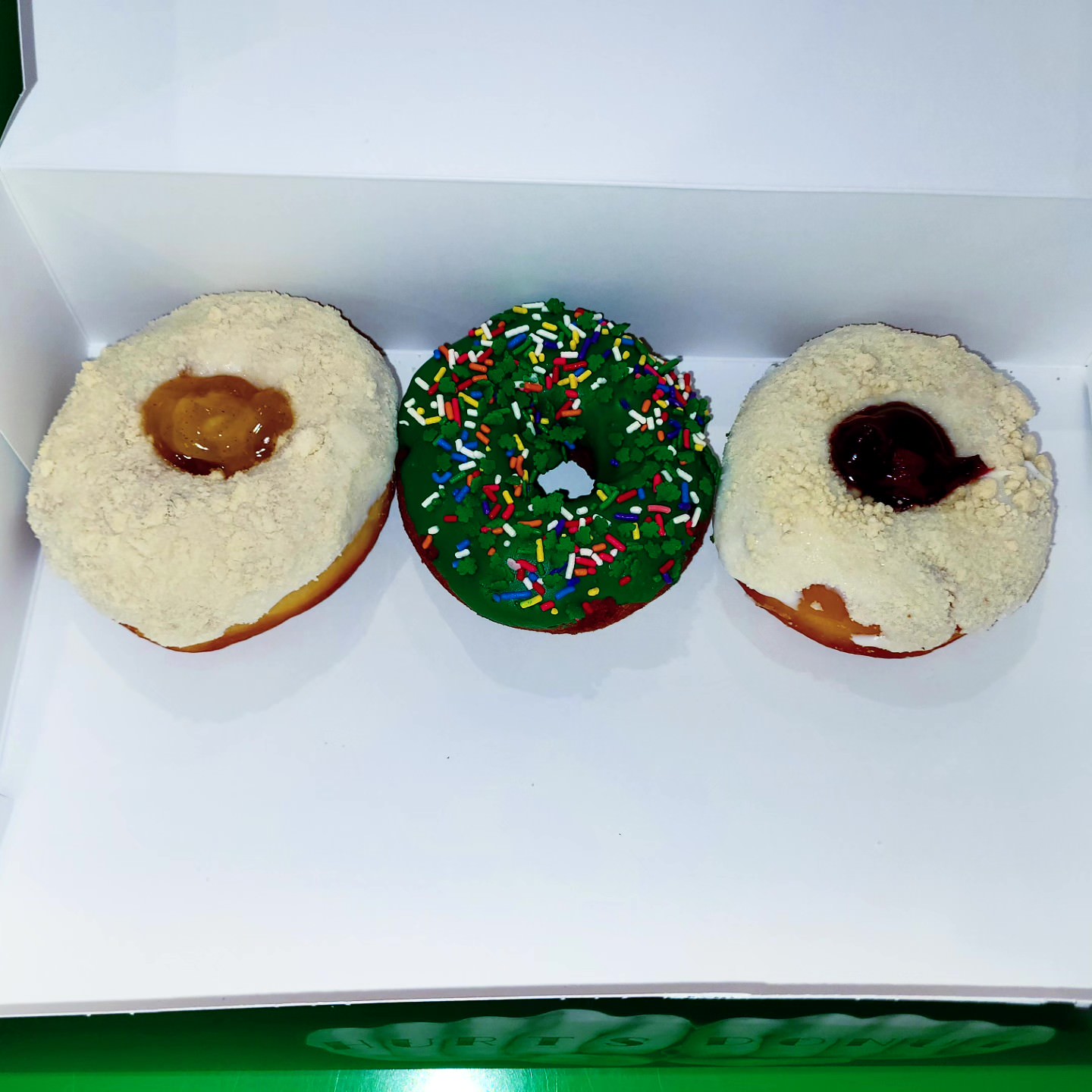 2023-03-14 0525 hours - Apple Pie, St. Paddy's Day Sprinkle, and Cherry Pie Doughnuts at Hurts Donuts